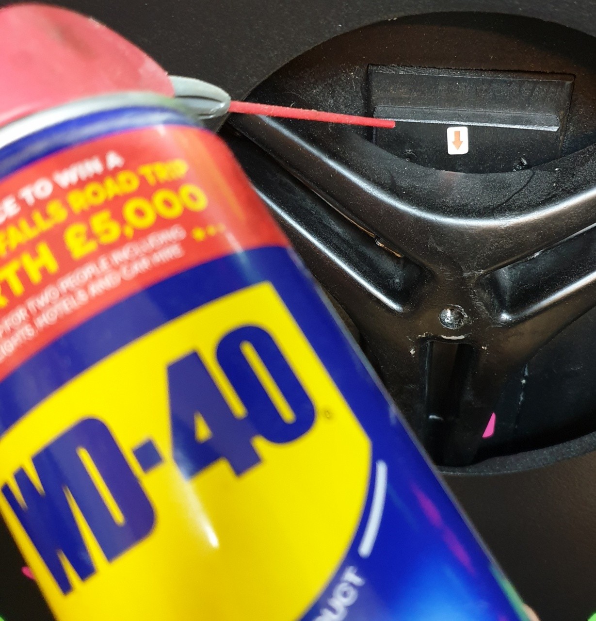 WD-40 straw pointing to the lubrication area behind the front cover.